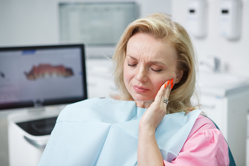 Mature woman having toothache sitting in dental chair